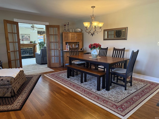 2110 Denson Ave, Bedford, IN 47421 - dining space featuring ceiling fan, wood finished floors, a chandelier, a glass covered fireplace, and baseboards