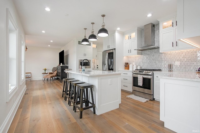 4 Edgewater Pl, Elkhart, IN 46516 - kitchen featuring wall chimney range hood, stainless steel appliances, a sink, backsplash, and light wood finished floors