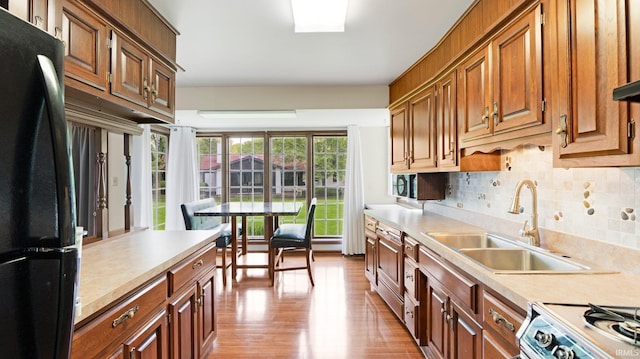 kitchen featuring freestanding refrigerator, light countertops, a sink, and backsplash