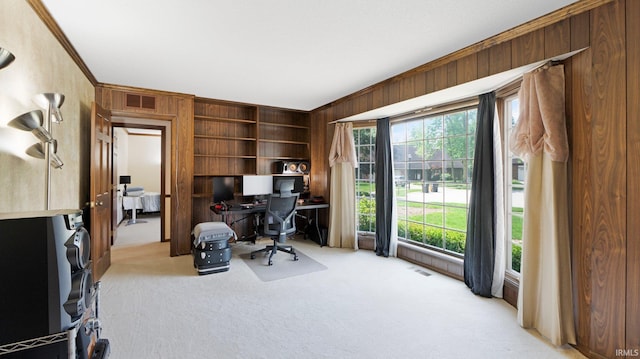 office space featuring light colored carpet, crown molding, wood walls, and built in shelves
