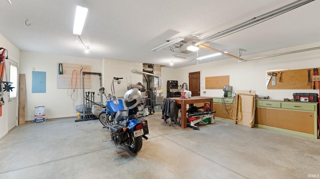 garage featuring electric panel, a garage door opener, and a workshop area
