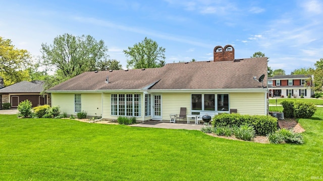 back of property with a patio, a lawn, and a chimney