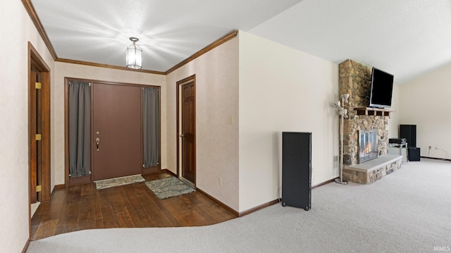 entrance foyer with a fireplace, carpet floors, baseboards, ornamental molding, and wood finished floors