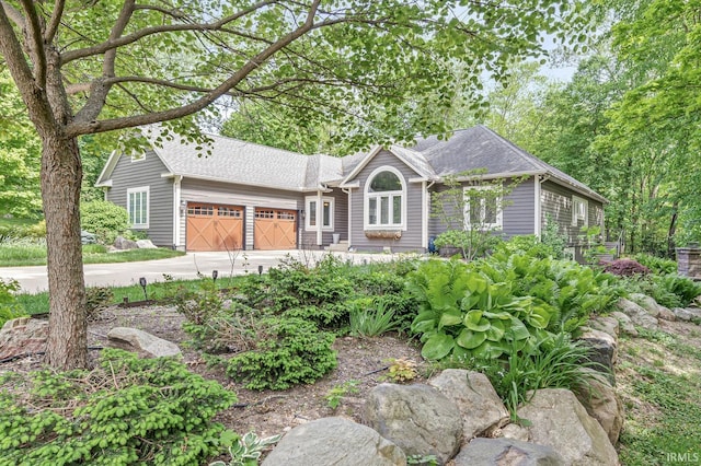 view of front of property featuring a garage, concrete driveway, and a shingled roof