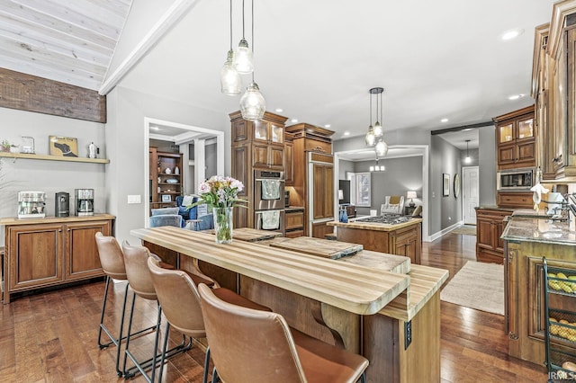 kitchen featuring a kitchen island, appliances with stainless steel finishes, brown cabinetry, recessed lighting, and dark wood finished floors