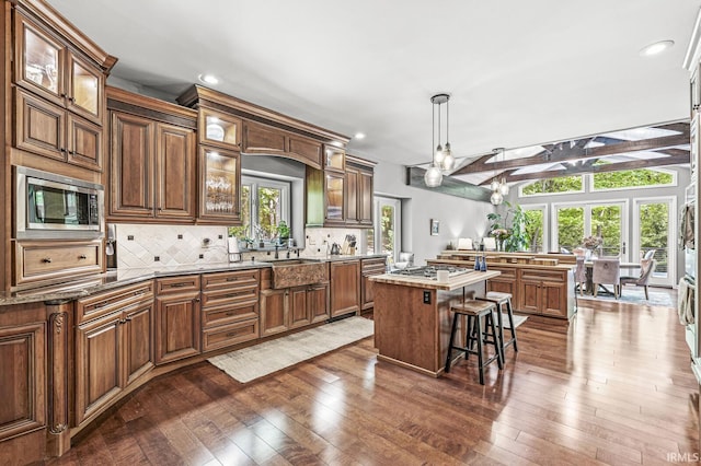 kitchen featuring appliances with stainless steel finishes, a breakfast bar, a kitchen island, dark wood-style flooring, and tasteful backsplash