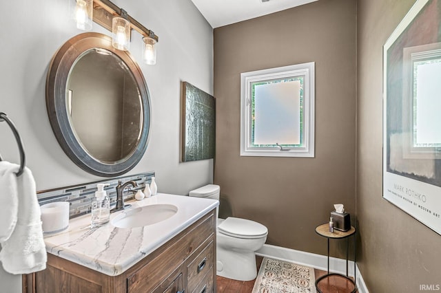 bathroom with healthy amount of natural light, toilet, vanity, and baseboards