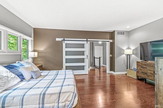bedroom with a barn door, wood finished floors, and baseboards