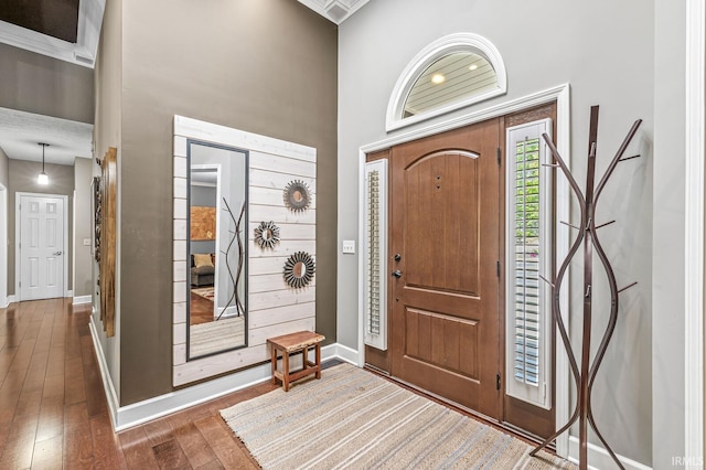 foyer with wood-type flooring, baseboards, and a high ceiling
