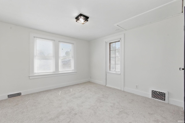 carpeted spare room featuring attic access and baseboards