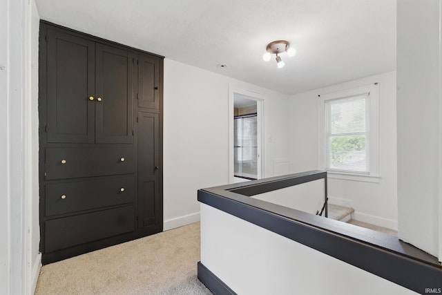 corridor with baseboards and light carpet