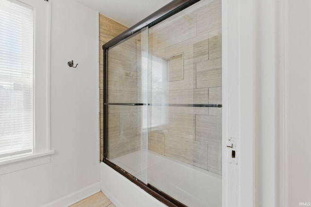 full bath with baseboards and combined bath / shower with glass door