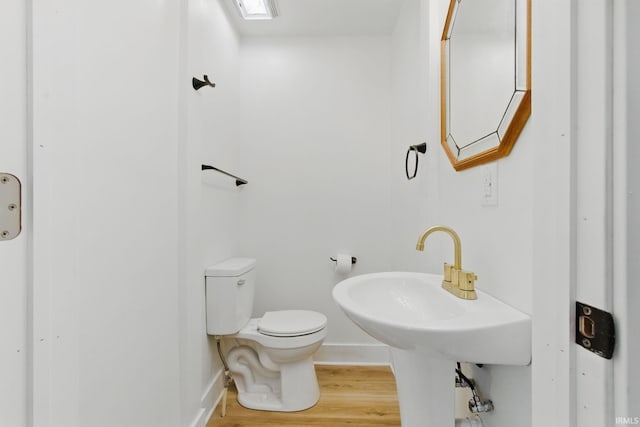 bathroom with toilet, wood finished floors, and baseboards