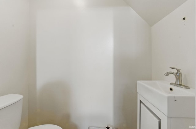 bathroom with toilet, vanity, and vaulted ceiling