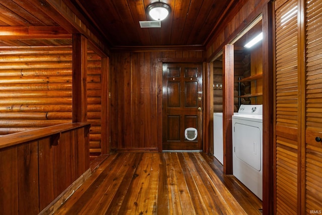 washroom with washer and clothes dryer, wooden ceiling, dark wood-style floors, and rustic walls