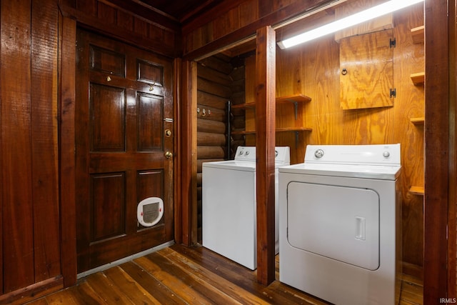 clothes washing area with washing machine and dryer, dark wood finished floors, and rustic walls