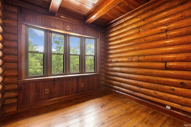 empty room featuring wooden ceiling, beamed ceiling, healthy amount of natural light, and wood-type flooring