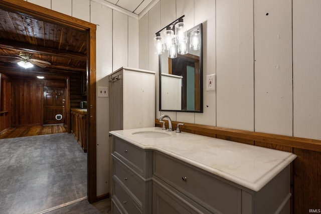 bathroom with ceiling fan, vanity, wood walls, wood ceiling, and a decorative wall