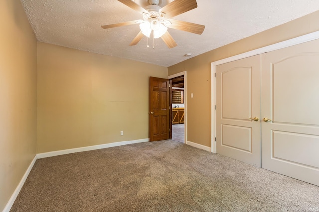 unfurnished bedroom with carpet floors, a textured ceiling, baseboards, ceiling fan, and a closet