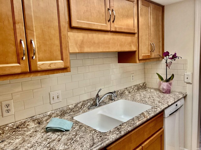 4501 N Wheeling Ave Unit 2-303, Muncie, IN 47304 - kitchen featuring white dishwasher, a sink, backsplash, brown cabinets, and light stone countertops