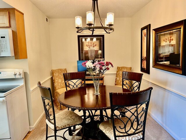 4501 N Wheeling Ave Unit 2-303, Muncie, IN 47304 - dining area with washer / dryer, a chandelier, light carpet, a textured ceiling, and baseboards