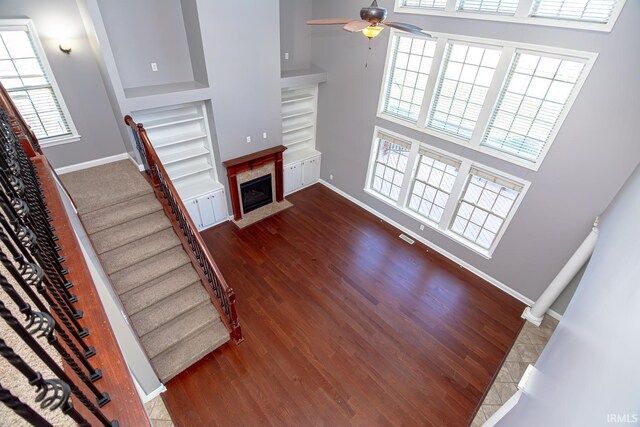 3905 Rushgrove Dr, Lafayette, IN 47909 - unfurnished living room featuring built in features, a towering ceiling, a ceiling fan, wood finished floors, and baseboards