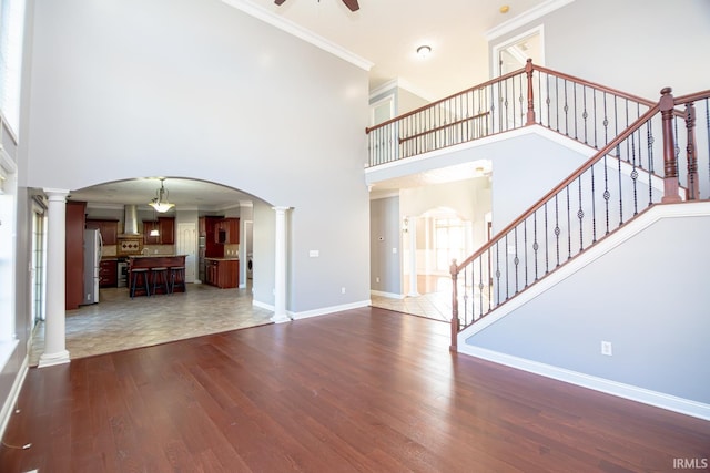 3905 Rushgrove Dr, Lafayette, IN 47909 - unfurnished living room with decorative columns, a high ceiling, dark wood-style floors, stairway, and a ceiling fan