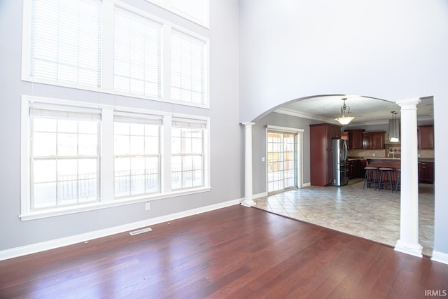 3905 Rushgrove Dr, Lafayette, IN 47909 - unfurnished living room with ornate columns, arched walkways, wood finished floors, a high ceiling, and baseboards