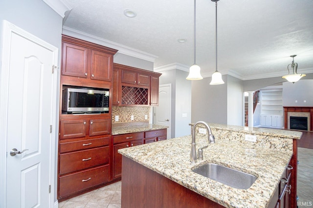 3905 Rushgrove Dr, Lafayette, IN 47909 - kitchen with a sink, stainless steel microwave, reddish brown cabinets, pendant lighting, and backsplash