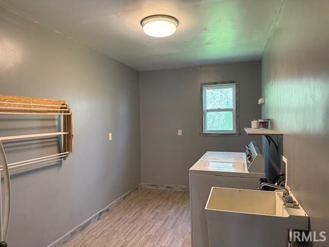laundry room featuring light wood-style flooring, independent washer and dryer, and baseboards