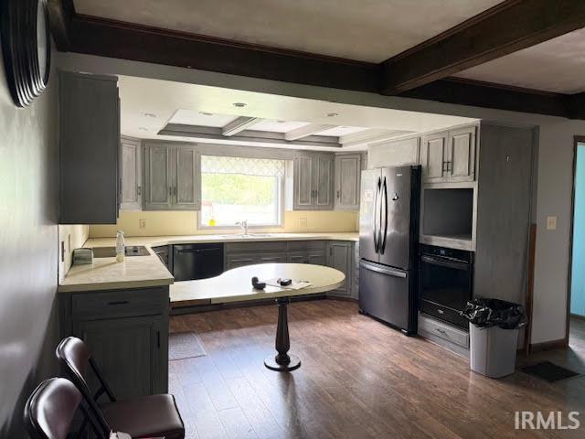 kitchen with black appliances, beam ceiling, dark wood-style floors, gray cabinetry, and light countertops