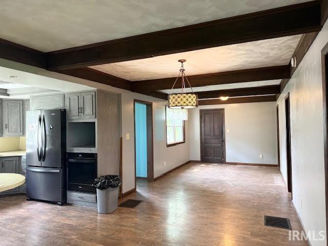 kitchen with freestanding refrigerator, oven, beamed ceiling, baseboards, and wood finished floors