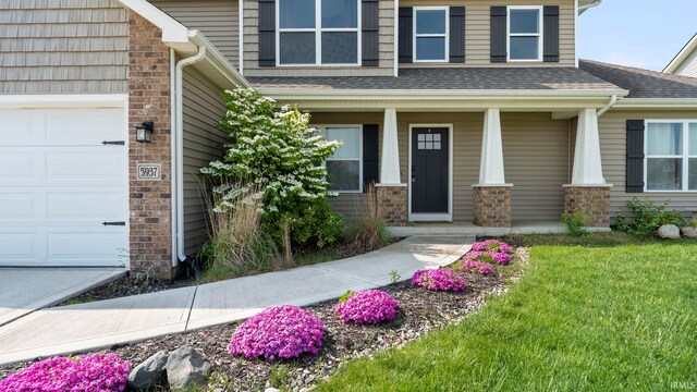 5937 Liam Ln, Fort Wayne, IN 46818 - entrance to property featuring covered porch, a garage, a shingled roof, and a lawn