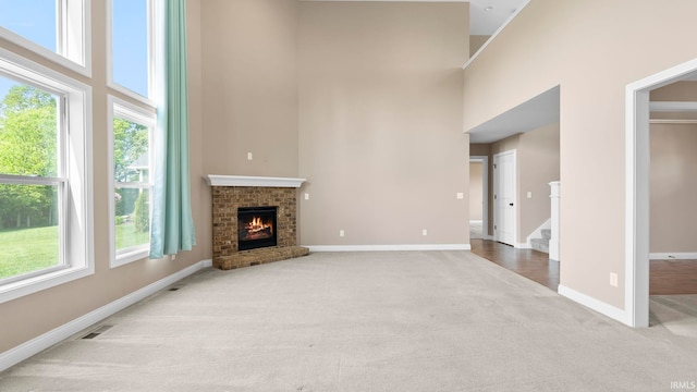 5937 Liam Ln, Fort Wayne, IN 46818 - unfurnished living room with a towering ceiling, carpet floors, baseboards, a fireplace, and stairs