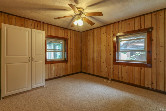 511 Pearl St, Rockport, IN 47635 - spare room featuring light carpet, wood walls, a textured ceiling, a ceiling fan, and baseboards