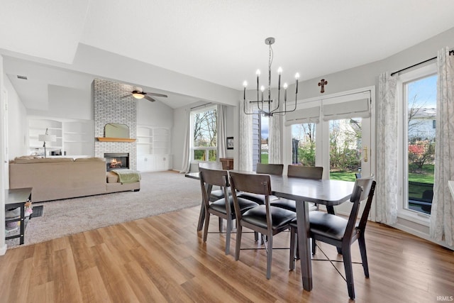 10731 Willow Creek Dr, Fort Wayne, IN 46845 - dining space featuring a fireplace, a chandelier, ceiling fan, wood finished floors, and built in shelves
