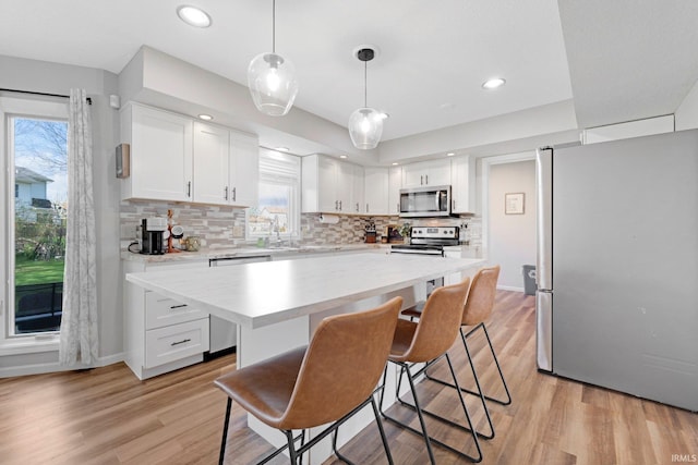 10731 Willow Creek Dr, Fort Wayne, IN 46845 - kitchen with appliances with stainless steel finishes, backsplash, white cabinetry, a kitchen bar, and light wood-style floors