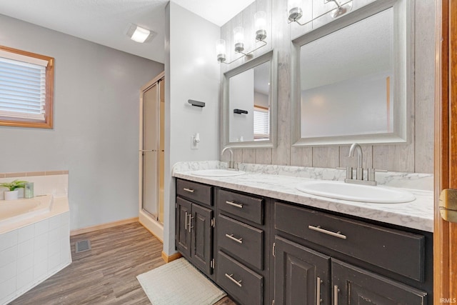 10731 Willow Creek Dr, Fort Wayne, IN 46845 - bathroom featuring a stall shower, double vanity, wood finished floors, a bath, and baseboards