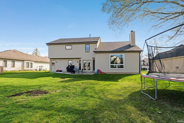 10731 Willow Creek Dr, Fort Wayne, IN 46845 - back of property featuring a trampoline, a chimney, a lawn, and french doors