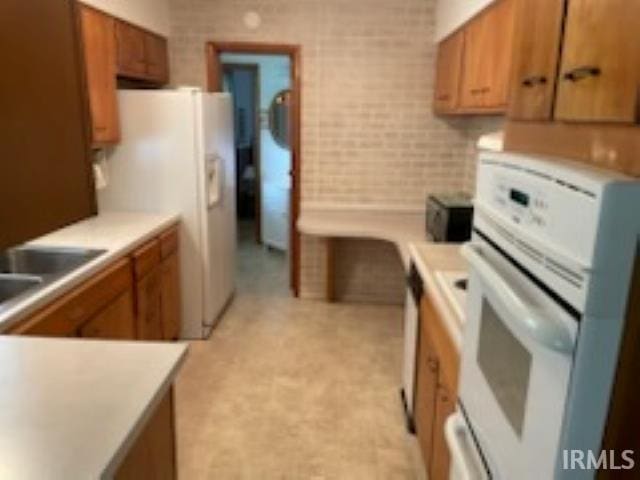 206 Pine St, Vincennes, IN 47591 - kitchen featuring white appliances, brown cabinetry, a sink, light countertops, and tile walls
