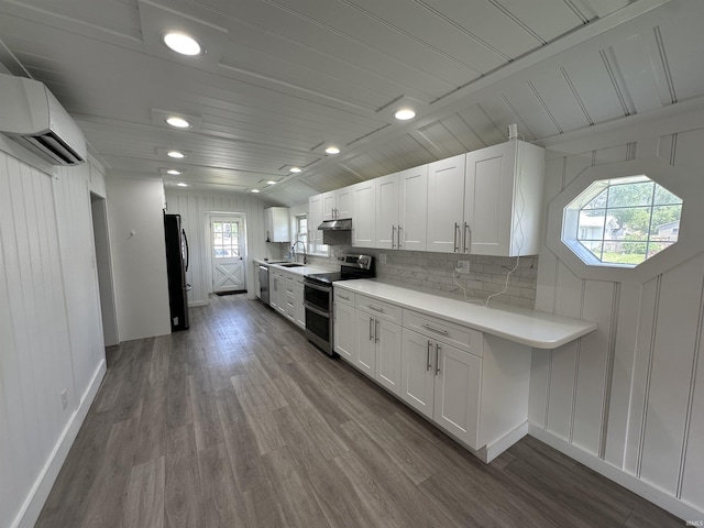 134 E 3rd St, Peru, IN 46970 - kitchen featuring stainless steel appliances, an AC wall unit, a sink, light countertops, and white cabinets