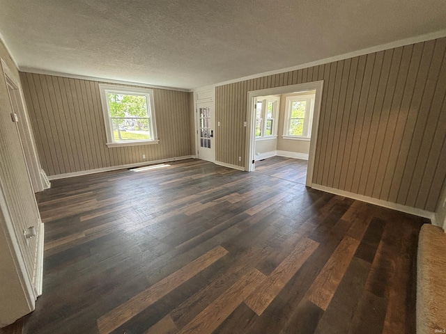 spare room with dark wood-style flooring, a textured ceiling, and baseboards