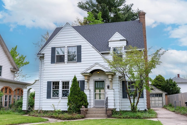 view of front of house featuring a chimney, entry steps, a garage, fence, and roof with shingles