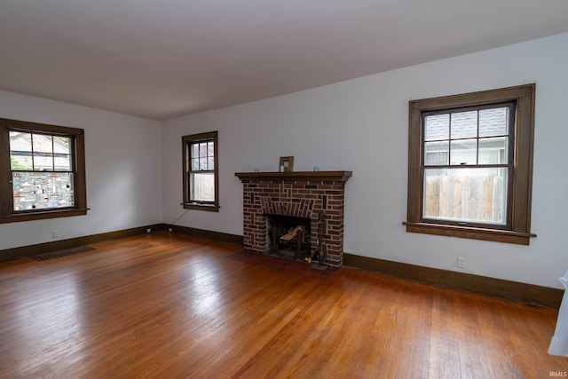 unfurnished living room with wood finished floors, plenty of natural light, and baseboards