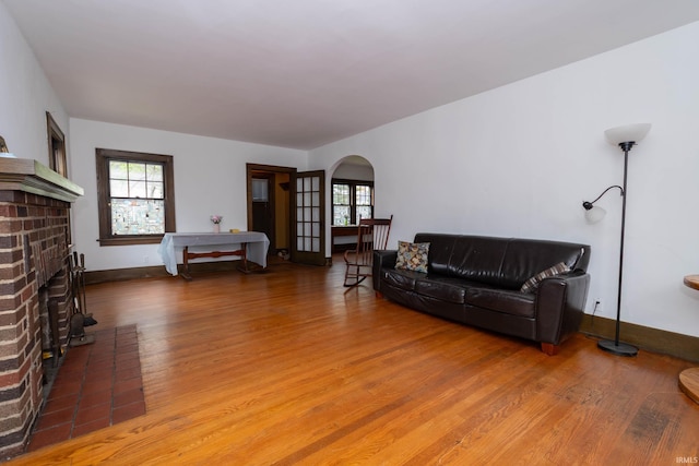 living room with wood finished floors, arched walkways, healthy amount of natural light, and a fireplace
