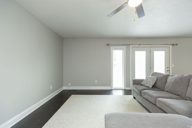 living area featuring dark wood-type flooring, baseboards, and ceiling fan