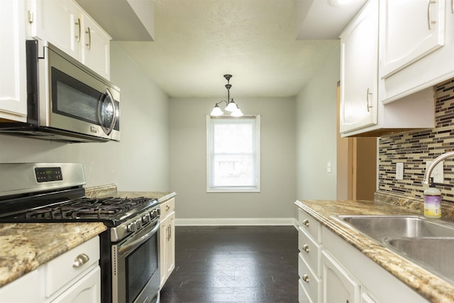 kitchen with stainless steel appliances, a sink, backsplash, and white cabinetry