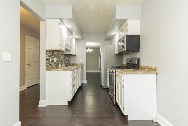 kitchen with appliances with stainless steel finishes, baseboards, light countertops, and a chandelier