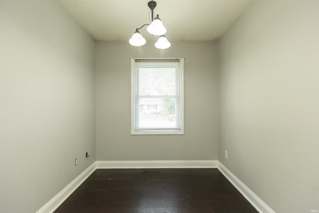 empty room with dark wood-style flooring, baseboards, and a chandelier
