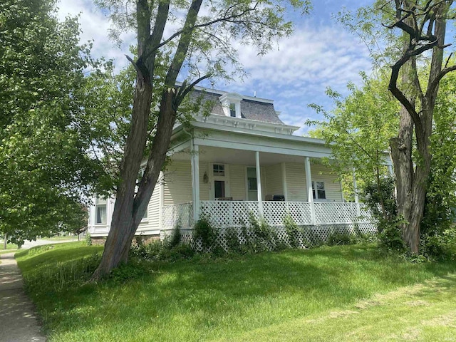 victorian home with mansard roof, a porch, and a front lawn